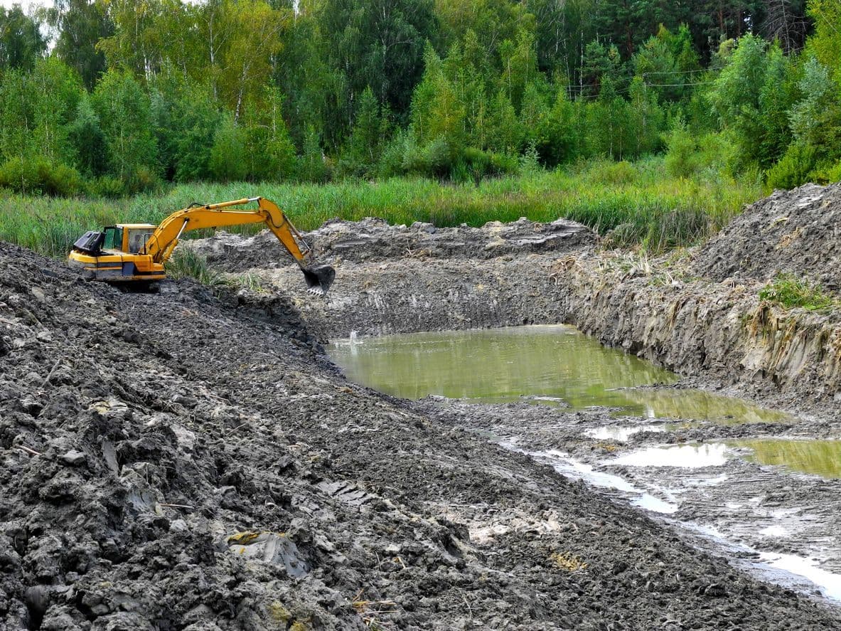 Excavator digging out a new pond on a rural property
